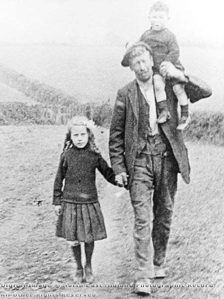 Miner walking home with his young children, carrying the younger child on his shoulder